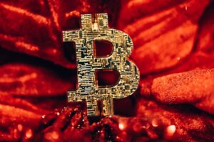 a golden bitcoin sitting on top of a red blanket